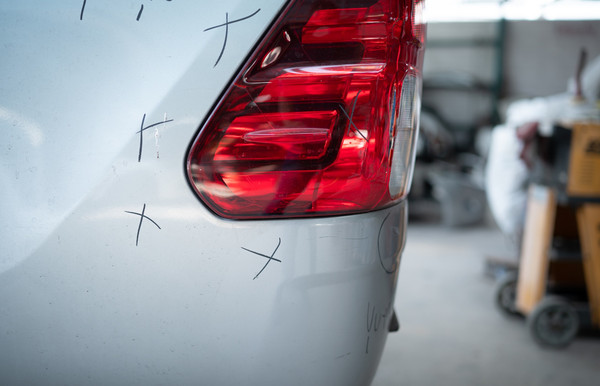 A car mechanic checks the condition of a car body to be repaired after a collision.